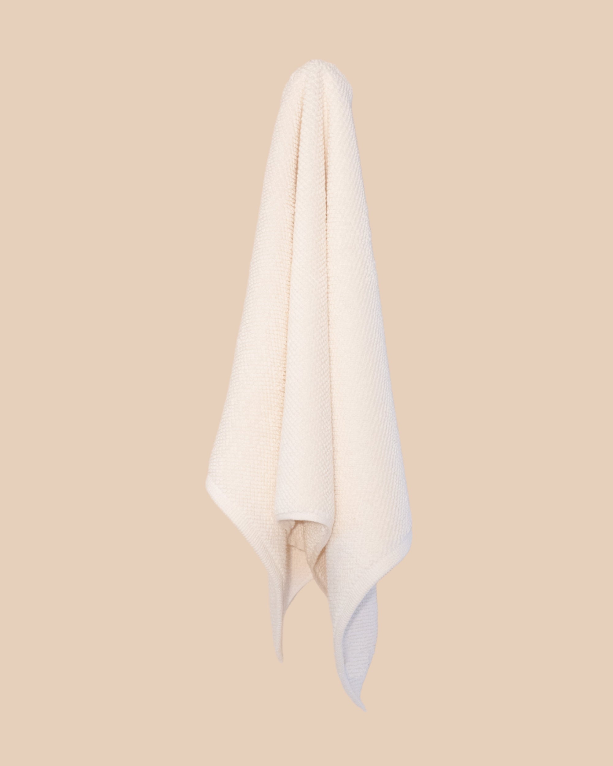 White hand  towel hanging against a beige background