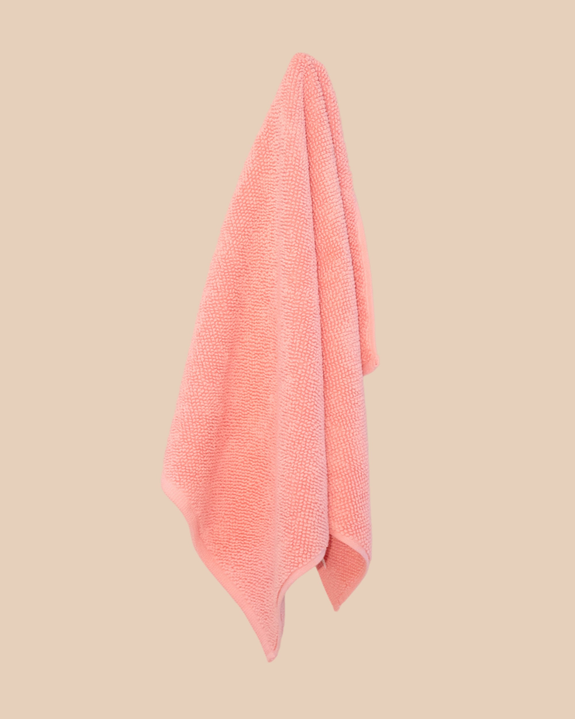 Pink bathmat with a chunky cotton weave hanging on a butter yellow background.