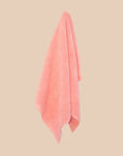 Pink bathmat with a chunky cotton weave hanging on a butter yellow background.