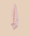 Lilachand  towel with orange stripes and 'kobn' logo on a beige background