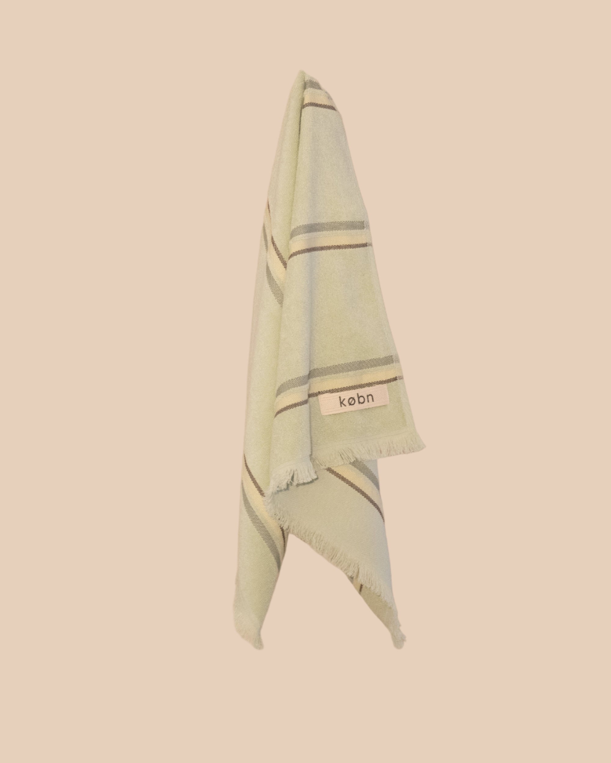 Light green hand towel with striped pattern and 'kebn' label on a beige background
