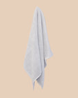 Light blue textured bathmat hanging against a beige background