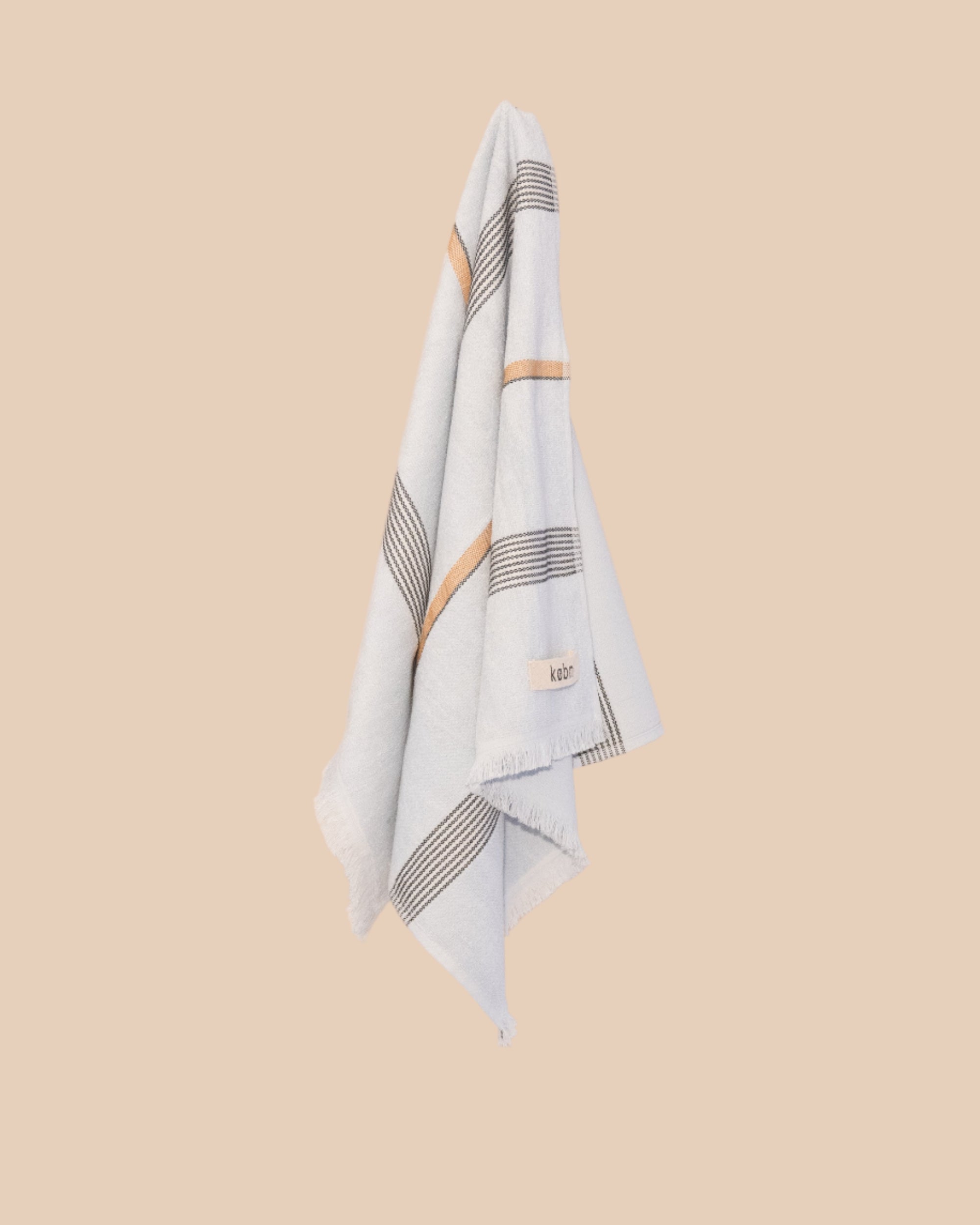 Pale Blue hand towel with stripes and fringing hanging on a butter yellow wall. 