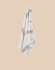 Pale Blue hand towel with stripes and fringing hanging on a butter yellow wall. 