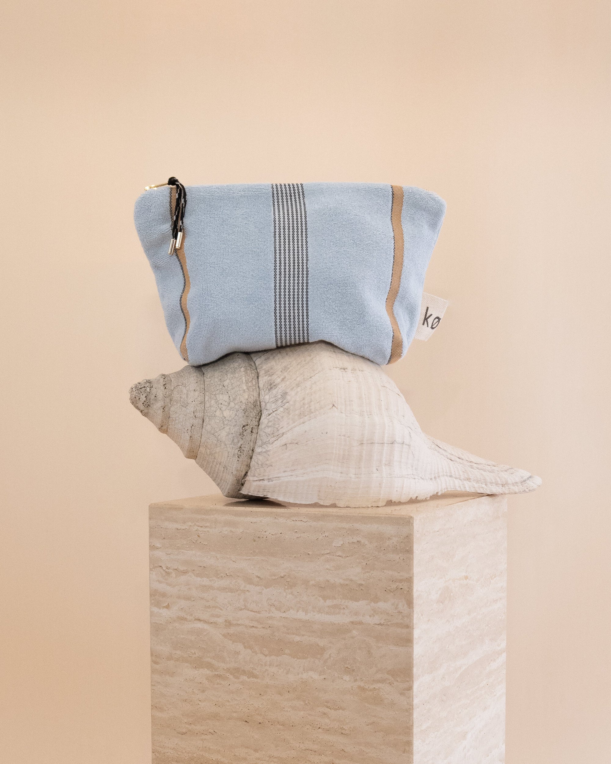 Light blue pouch with striped pattern on a beige background