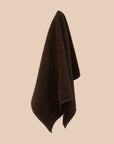 Brown textured bathmat hanging on a beige wall