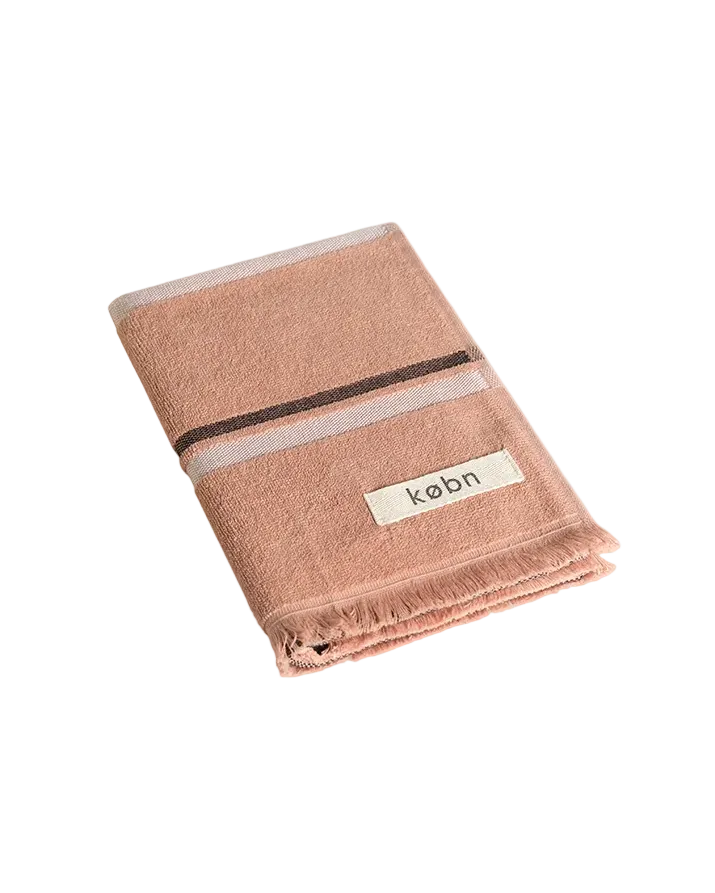 Folded Clay coloured hand towel with black and cream stripes and raw edge fringing. 