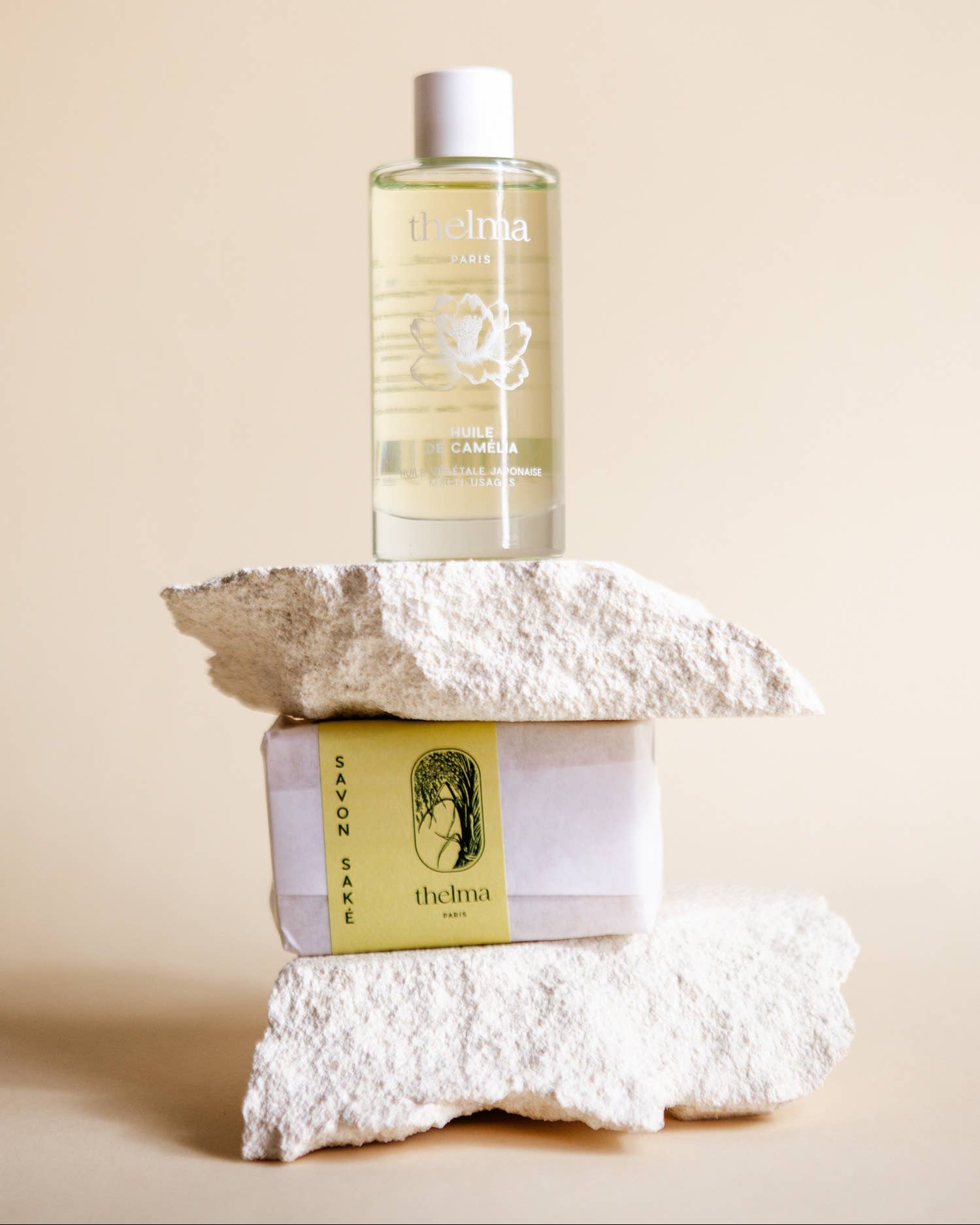 Bottle of skincare product on a stack of white stones with a beige background