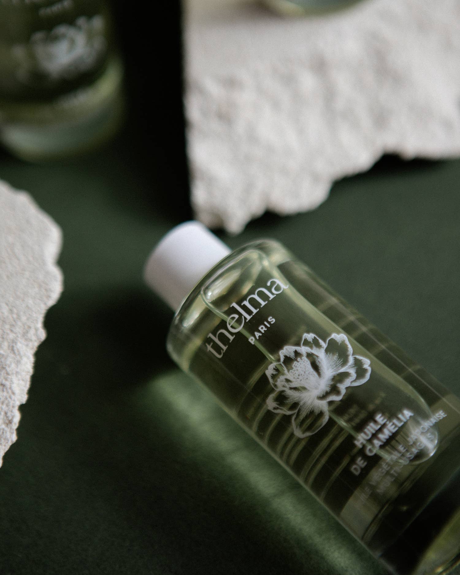 Thealma Paris bottle on a dark surface with a blurred background